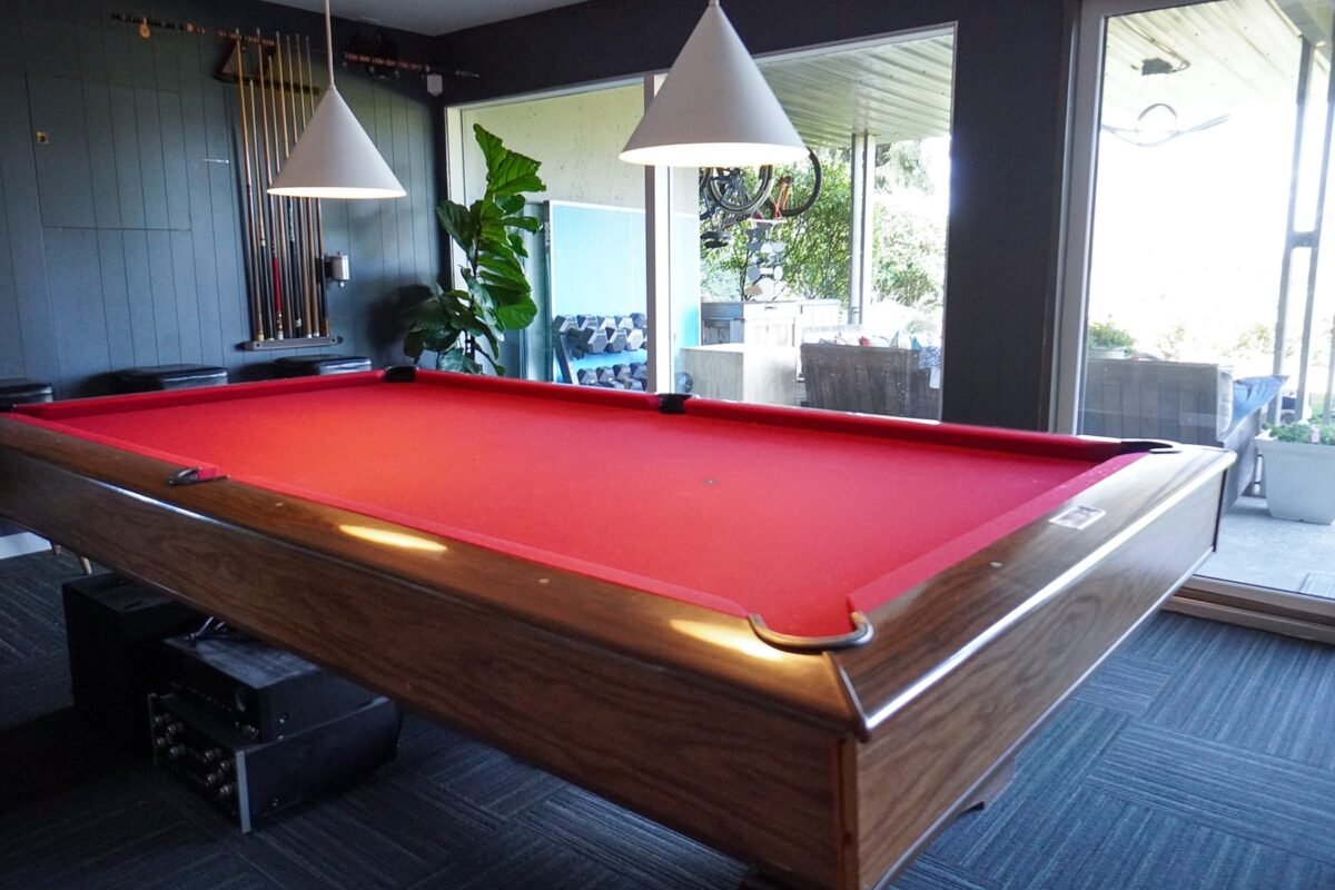 Entertainment room featuring a red felt pool table and sliding doors to the patio at Naakef Travel Nurse Stay – Lake Forest Park.