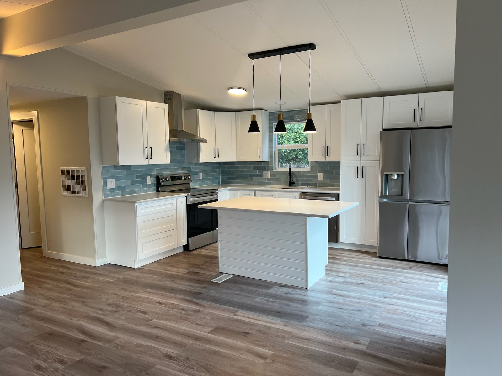 Modern furnished rental kitchen in SeaTac – white shaker cabinets, blue-green tile backsplash, furnished short term rental property with stainless steel appliances and natural light