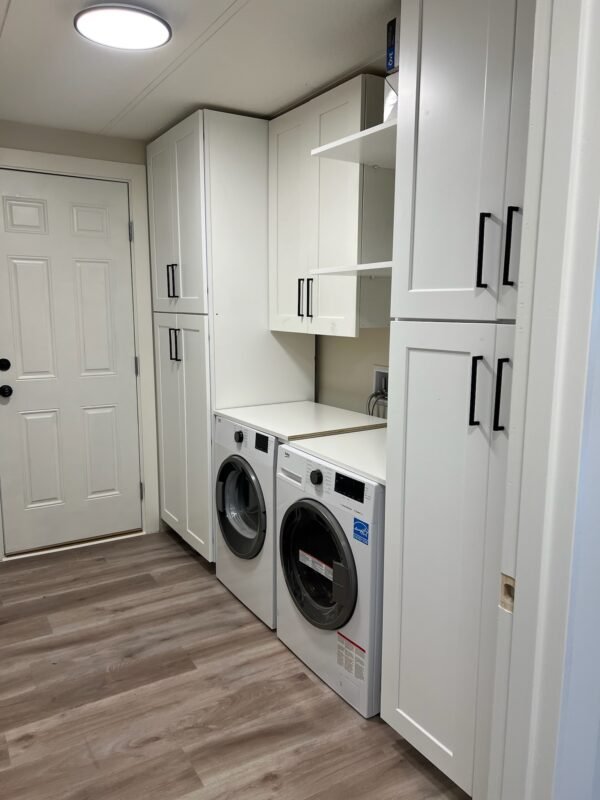 Convenient laundry area equipped with modern front-loading washer and dryer alongside ample storage cabinets at Naakef Private Home Rentals – Seatac.