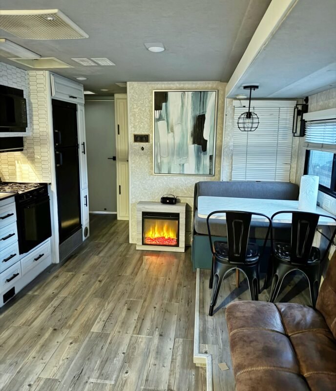 Fully equipped RV kitchen featuring a modern stove, hexagon tile backsplash, and cozy dining area with fireplace at Naakef Private Home Rentals – Seatac.