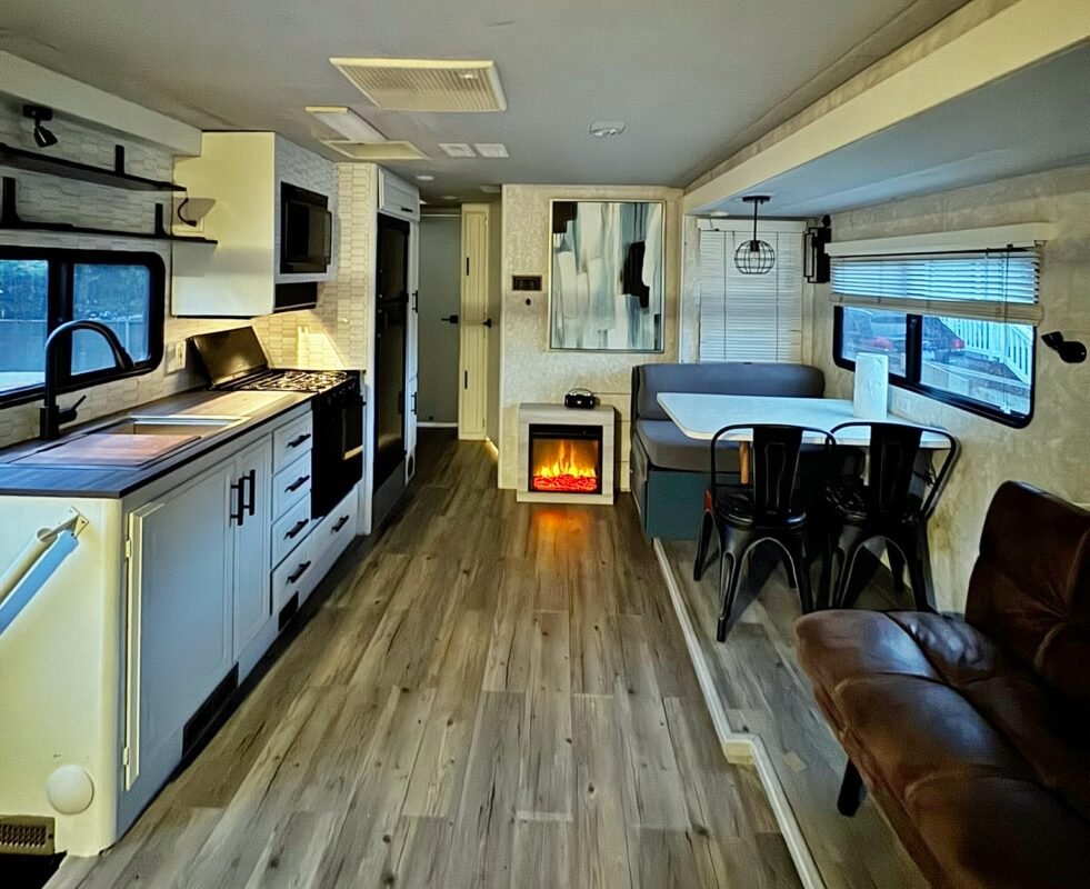 Inviting RV living space featuring a warm fireplace, comfortable dining booth, and wood-style flooring at Naakef Private Home Rentals – Seatac.