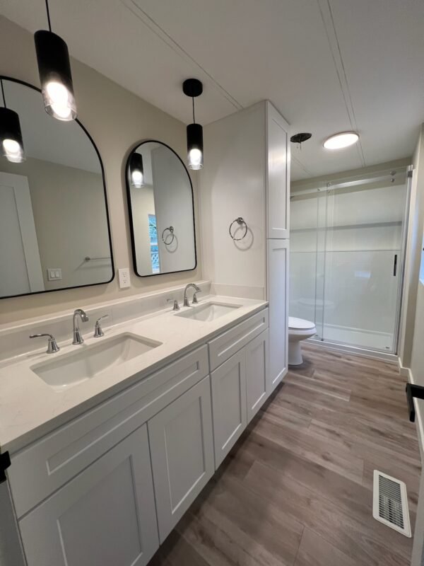 Elegant bathroom with a double sink vanity, two arched mirrors, and modern black light fixtures at Naakef Private Home Rentals – Seatac.