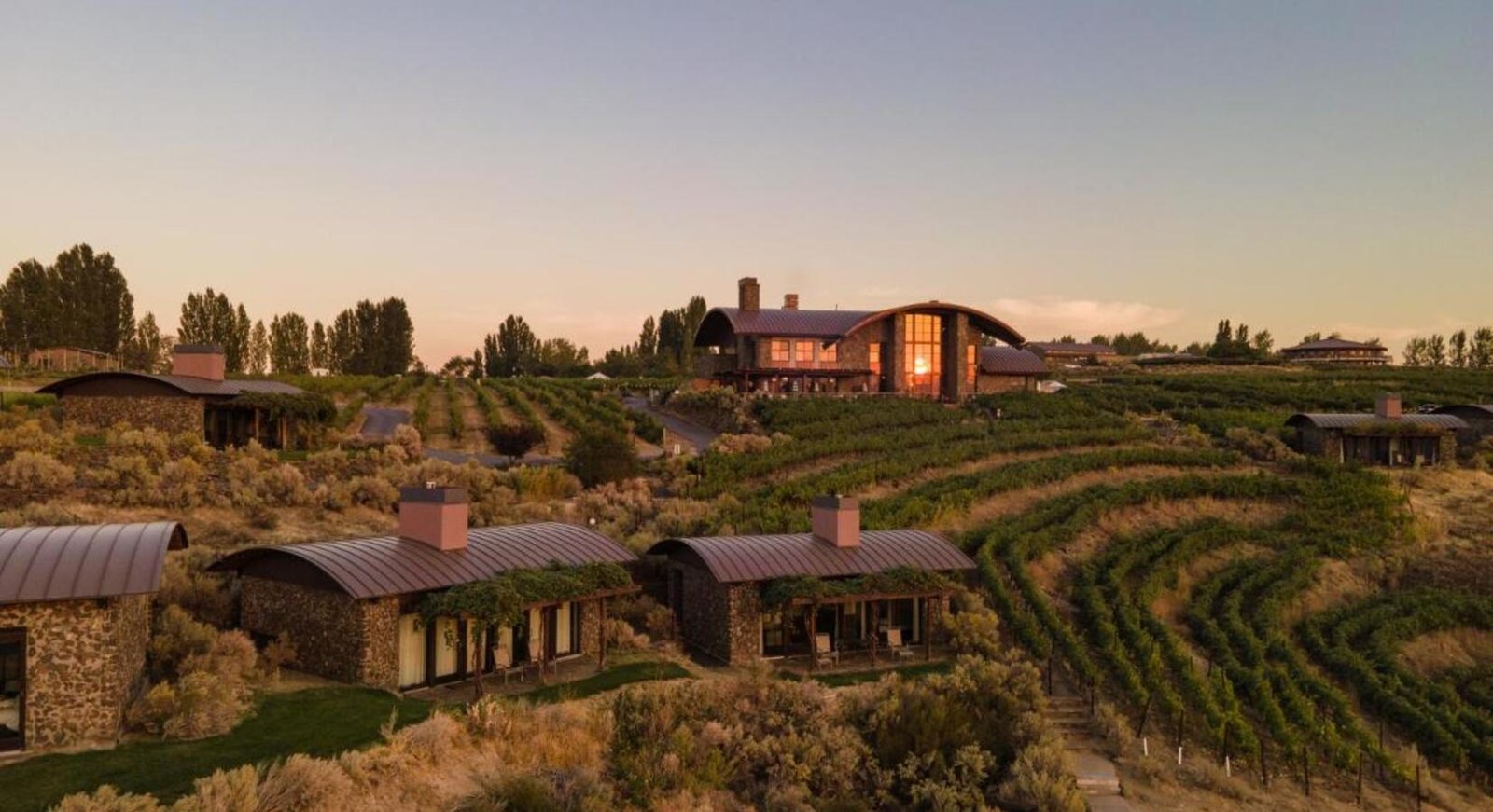 Sweeping golden hour view of the entire Sagecliffe Residences by Naakef estate showcasing stone cabins, vineyards, and the main pavilion nestled among the gorge terrain.