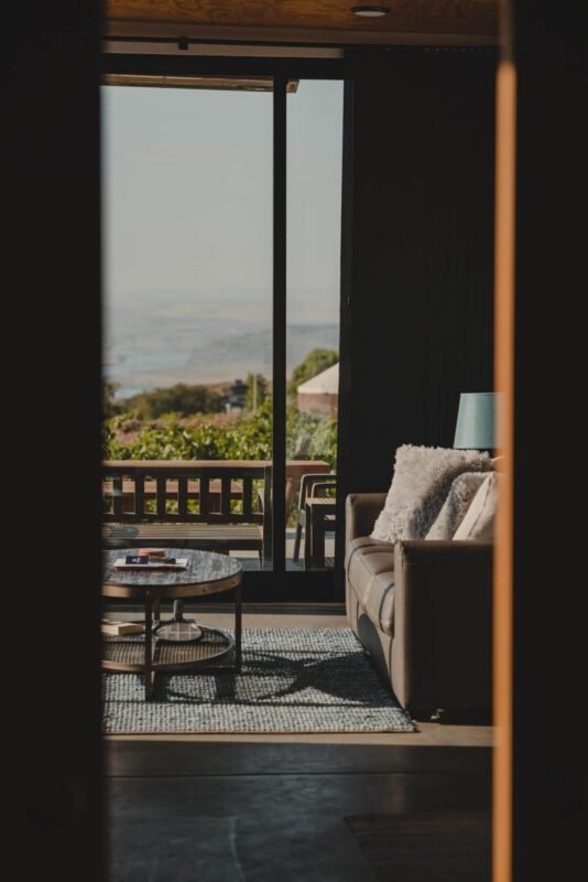 View from a comfortable living room looking out through sliding glass doors to the scenic outdoor terrace and landscape at Sagecliffe Residences by Naakef.
