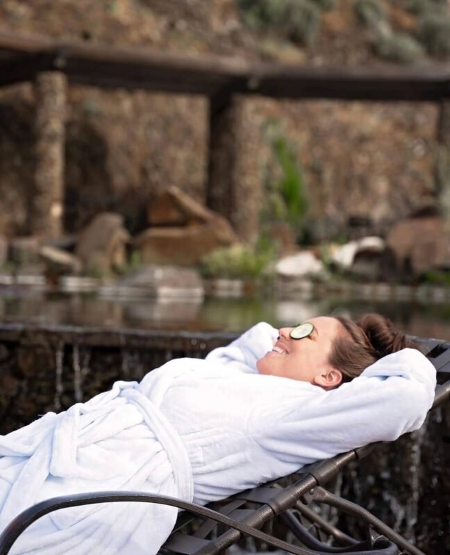 Guest enjoying a peaceful moment in a reclining chair overlooking the serene river landscape at Sagecliffe Residences by Naakef.