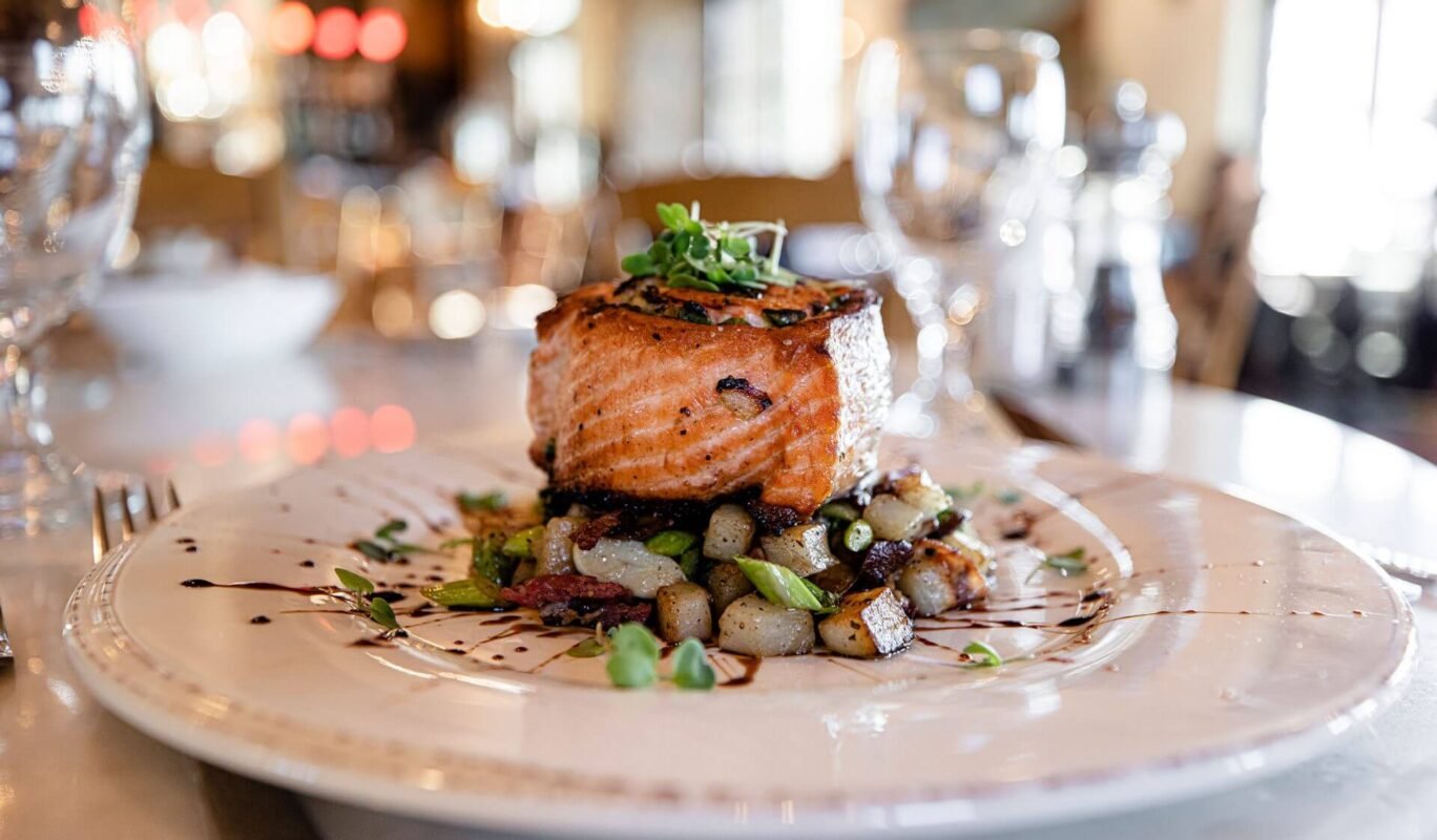 Elegantly plated salmon fillet with roasted potatoes and green vegetables served at the fine dining establishment at Sagecliffe Residences by Naakef.