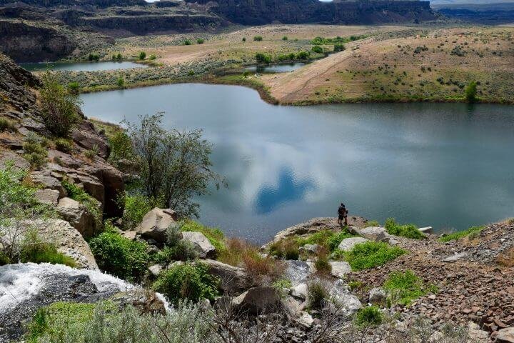 Serene mirror-like lake surrounded by dramatic rocky cliffs and green landscape near Sagecliffe Residences by Naakef in the Columbia River Gorge region.